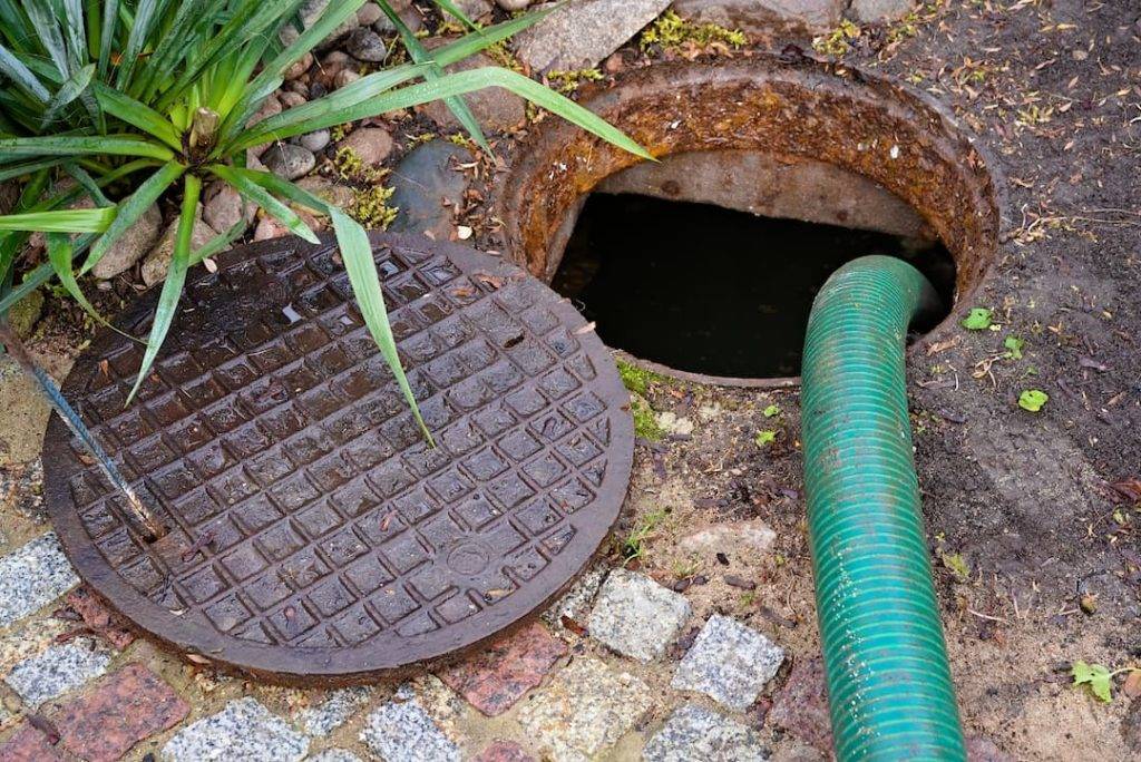 Drain Cover Of A Cesspit Open With A Pipe Leading Into The Hole
